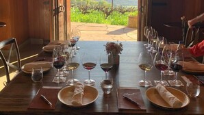 Una mesa lista para comer, con copas de vino, platos y un jarrón de flores.