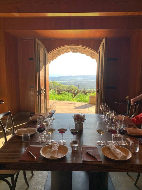 Una mesa lista para comer, con copas de vino, platos y un jarrón de flores.