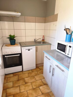 A compact kitchen with a stove, oven, dishwasher, sink, and microwave.