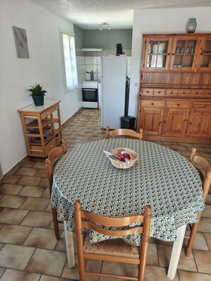 Een eethoek met een ronde tafel, vier stoelen, een klein kastje en een potplant.
