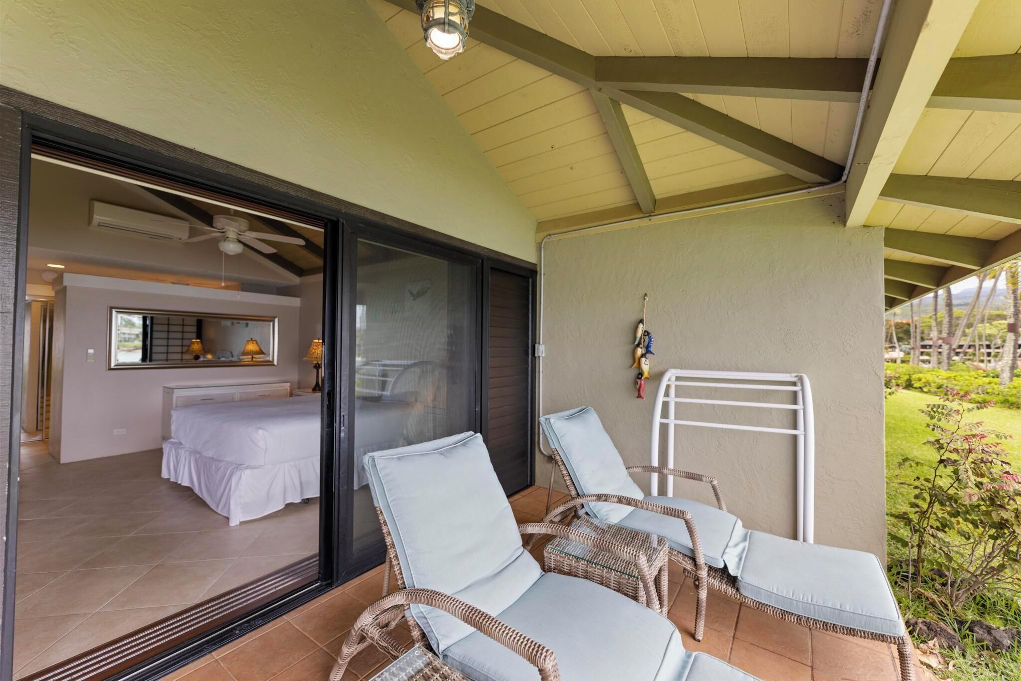 A covered outdoor seating area with wicker chairs and a white ladder.