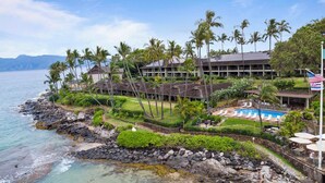 A resort with a pool, palm trees, and a view of the ocean. - Napili Lani 315  2BD Beachfront Luxury (Lahaina)