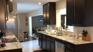 A modern kitchen with dark cabinets, stainless steel appliances, and a marble countertop. - Tropical pool home close to the beach, never floods, high and dry  (Seminole)