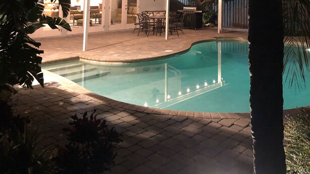 A swimming pool with a covered patio area, palm trees, and a view of the sky. - Tropical pool home close to the beach, never floods, high and dry  (Seminole)