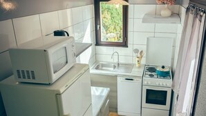 Una cucina compatta con microonde, frigorifero, lavastoviglie, lavello e piano cottura.