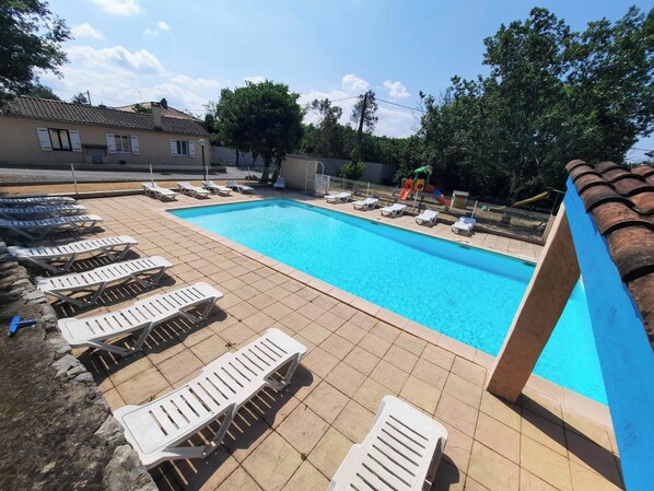 A swimming pool with lounge chairs and a slide.