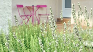 A patio area with a table and chairs, surrounded by greenery.