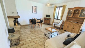 Una sala de estar con sofá, mesa de centro, televisor, chimenea y un comedor con sillas y mesa.
