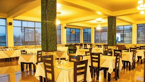 A restaurant with multiple tables and chairs, large windows, and a polished floor.