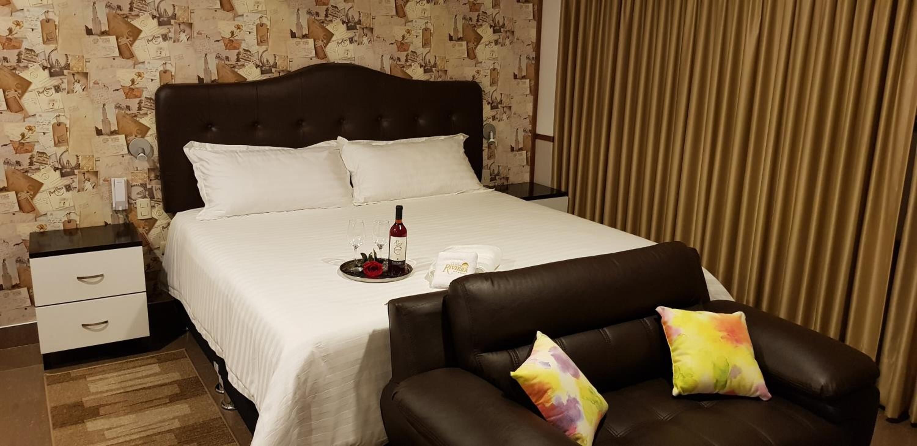 Una habitación de hotel con una cama, una mesita de noche, una silla y una cortina.