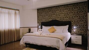 Una camera d'albergo con un letto, un comodino, una ventola a soffitto e un muro decorato.