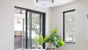 A modern dining area with a round table, grey chairs, a white rug, and a large window with a view of a snowy landscape. - Outpost: One Town Hill 507 - Base of Snow King Mtn (Jackson)