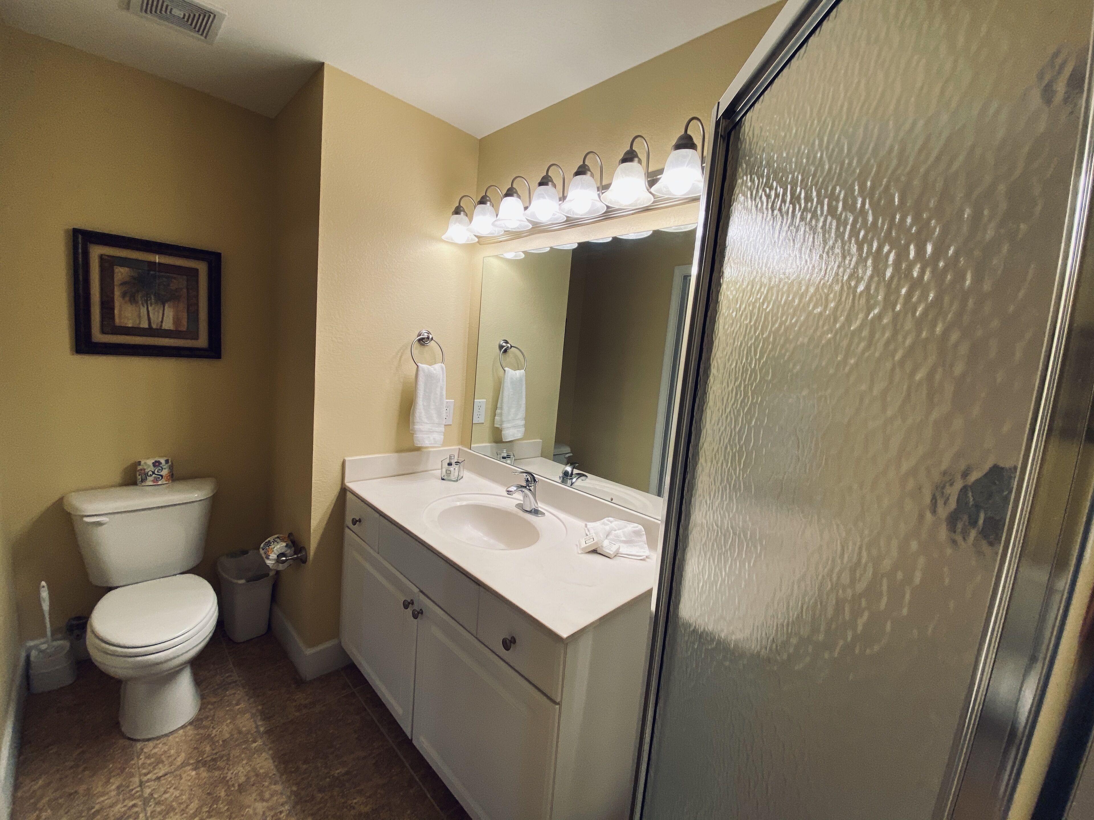 A bathroom with a toilet, sink, and mirror.