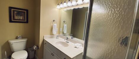 A bathroom with a toilet, sink, and mirror.