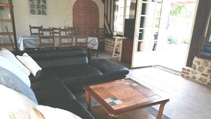 Un salon avec un canapé noir, une table basse en bois et un sol carrelé.