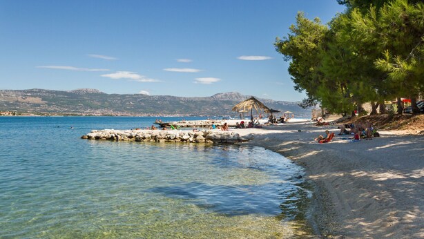 A beach with clear water, a rocky breakwater, and people relaxing. - ARBANIJA A2, budget 1-bedroom apartment, 80m from the beach (Arbanija)