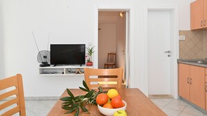 A dining area with a table, chairs, a TV, and a fruit bowl. - ARBANIJA A2, budget 1-bedroom apartment, 80m from the beach (Arbanija)