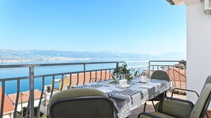 A balcony with a table set for two, overlooking a body of water and a distant coastline. - ARBANIJA A2, budget 1-bedroom apartment, 80m from the beach (Arbanija)