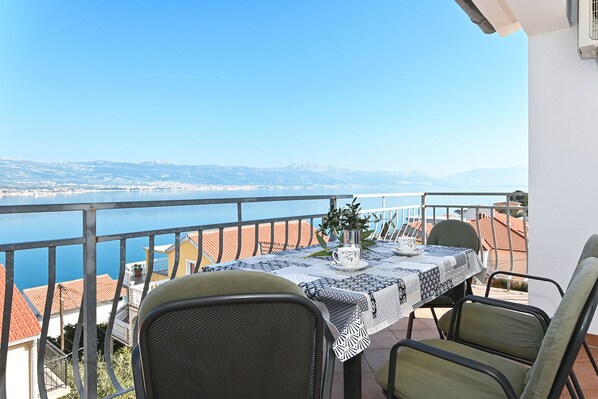 A balcony with a table set for two, overlooking a body of water and a distant coastline. - ARBANIJA A2, budget 1-bedroom apartment, 80m from the beach (Arbanija)