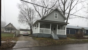 Une maison à deux étages avec un porche à l’avant et un garage.