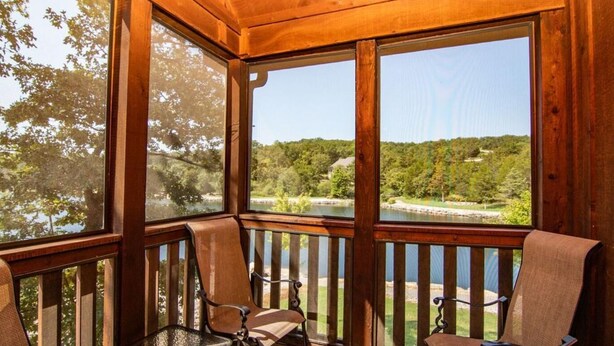 A wooden deck with two chairs facing a scenic view of a lake and forest. - Lake Front next to the Pool! In Stonebridge by Silver Dollar City (Branson West)