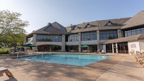 A hotel with a swimming pool, outdoor seating, and a large building with multiple windows. - Lake Front next to the Pool! In Stonebridge by Silver Dollar City (Branson West)