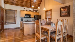 A kitchen with wooden cabinets, a dining table, and chairs. There are ceiling lights, a microwave, and a refrigerator. - Lake Front next to the Pool! In Stonebridge by Silver Dollar City (Branson West)
