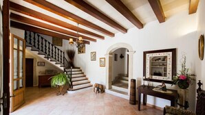 A spacious foyer with a staircase, a wooden bench, a console table with decorative items, and a large mirror.