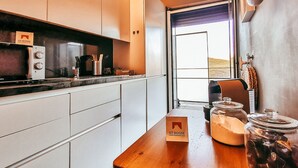 Een moderne keuken met witte kasten, een houten aanrechtblad en uitzicht op het groen.
