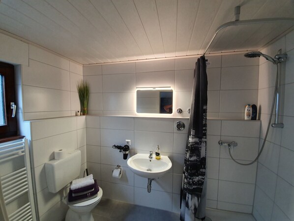 A bathroom with a toilet, sink, and shower.