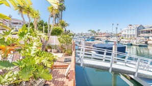 Un port de plaisance avec des bateaux amarrés, une terrasse en bois et des palmiers.