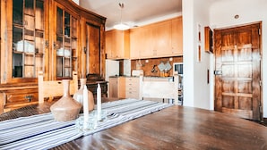 Un comedor con una mesa de madera, un camino de mesa a rayas y un aparador con puertas de cristal.