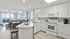 Une cuisine moderne avec des meubles blancs, un îlot central et une vue sur l’extérieur.