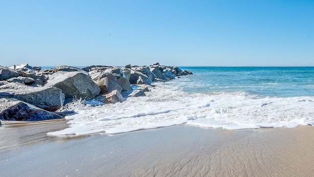 Ein Strand mit großen Felsen und Wellen.
