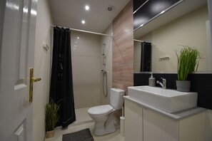 Ein modernes Badezimmer mit Toilette, Dusche, Waschbecken und Spiegel.
