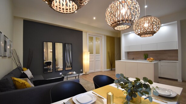 Una sala de estar moderna con comedor, que incluye un sofá, una mesa de comedor y una cocina al fondo.