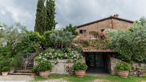 A rustic stone house with a garden, featuring potted plants and flowering shrubs. - UNDER THE TUSCAN SUN (scandicci)