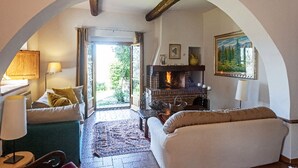 A cozy living room with a fireplace, comfortable seating, and a view through an archway. - UNDER THE TUSCAN SUN (scandicci)