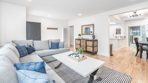 A modern living room with a grey sectional sofa, a white coffee table, and a wooden cabinet with a mirror.