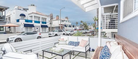 Un balcón con mobiliario exterior, vista a coches estacionados y edificios al fondo.