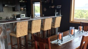 Una cocina moderna con una isla central, taburetes de bar y una mesa de comedor para seis personas.