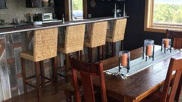 A modern kitchen with a central island, bar stools, and a dining table set for six.