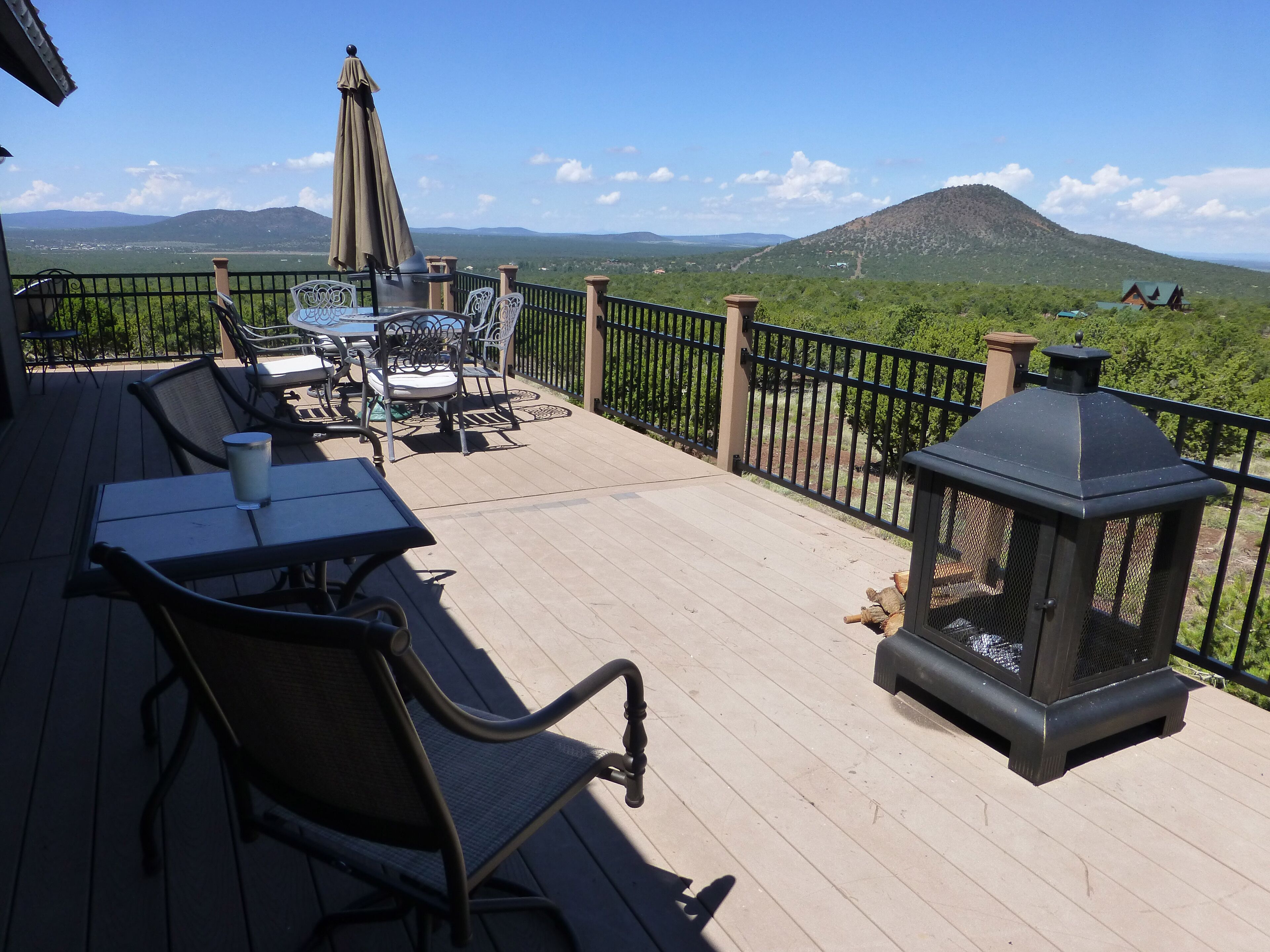 A deck with outdoor furniture, a lantern, and a view of a mountain and valley.