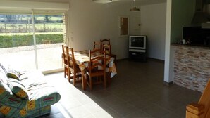 A spacious living area with a dining table, chairs, a sofa, a television, and a kitchen area. - GITE VERY COMFORTABLE IN THE COUNTRY, NICE VOLUMES PROMOTION IN JULY (Cours-de-Pile)
