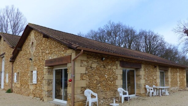 A stone building with a tiled roof, a gravel driveway, and white plastic chairs and tables outside. - GITE VERY COMFORTABLE IN THE COUNTRY, NICE VOLUMES PROMOTION IN JULY (Cours-de-Pile)