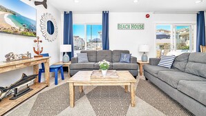 A beach-themed living room with a sofa, a coffee table, and decorative items like an anchor and a bird sculpture.