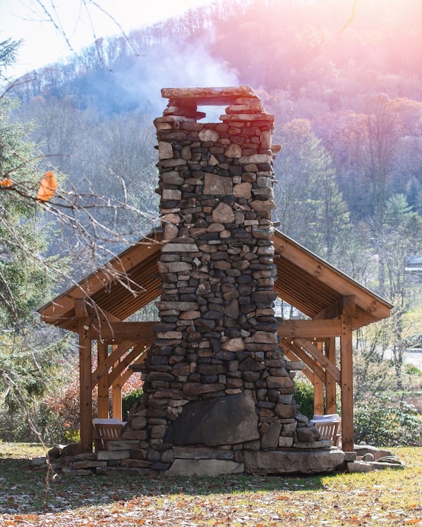 A stone structure with a wooden roof, surrounded by trees and a mountainous backdrop. - The Dogtrot in Dennis Cove - Creekside Cabin w/ Sauna, Hot Tub & AT Trail Access (Hampton)