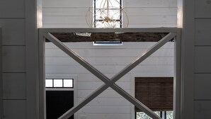 Une pièce avec un plafond en pente, un luminaire suspendu et une fenêtre donnant sur l’extérieur.