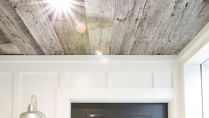 Une porte noire avec un panneau de verre, un luminaire au-dessus et un plafond en bois.