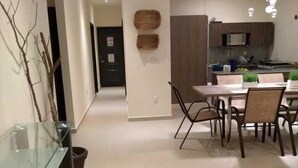 Une cuisine moderne équipée d’un four à micro-ondes, d’une cuisinière et d’un évier. On y trouve également un coin repas avec une table et des chaises en verre.